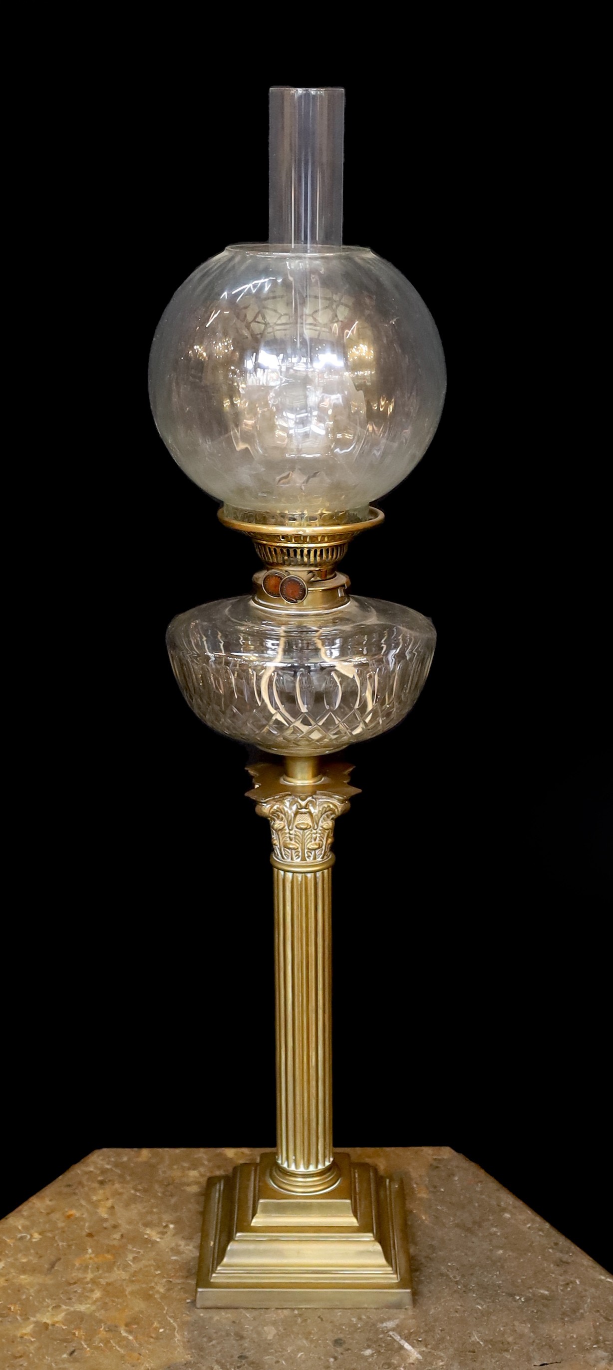A late Victorian/Edwardian Corinthian column brass oil lamp, with cut glass reservoir, J.R.Roberts mechanism, fluted glass globe and flue, height overall 83cm
